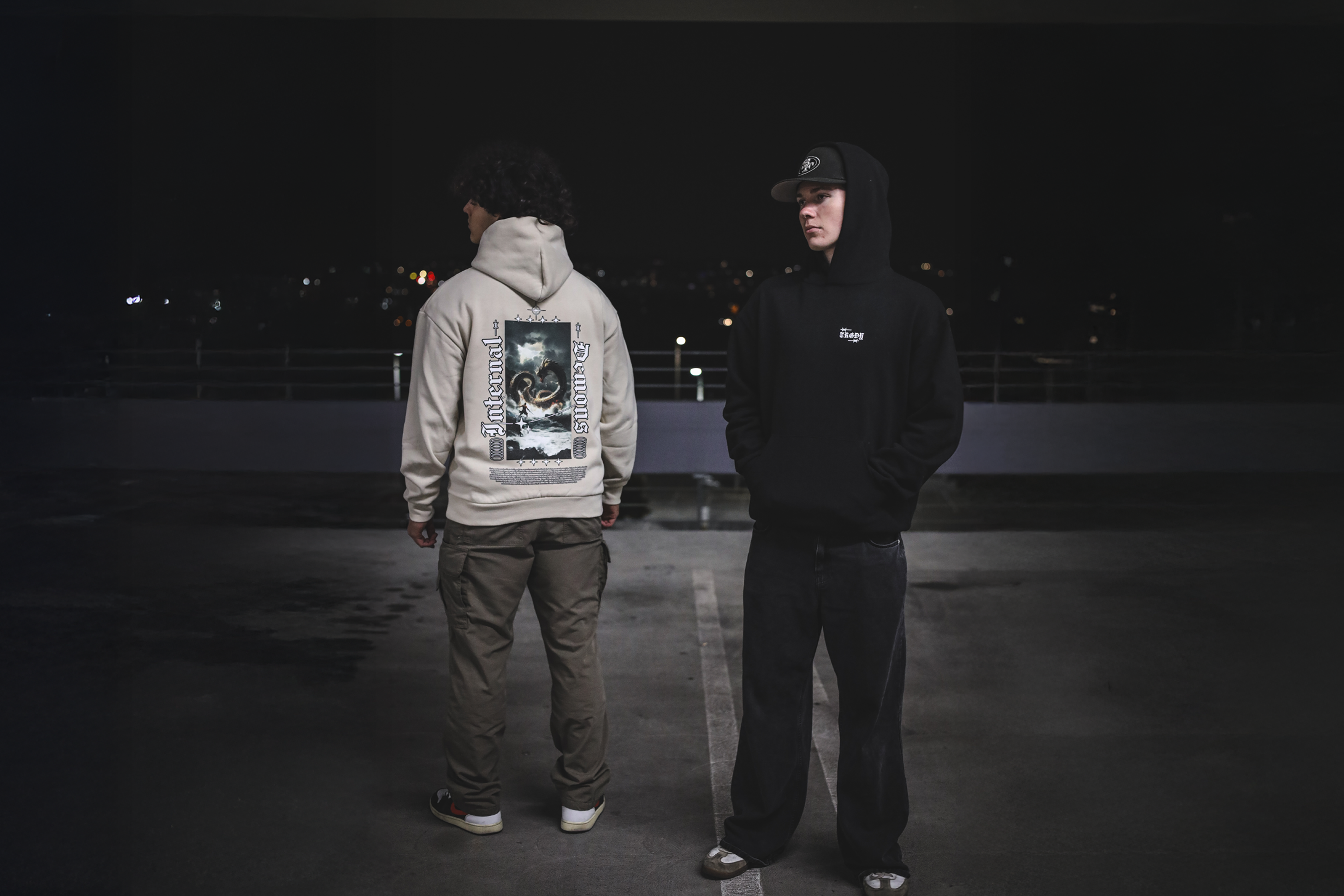 Two people wearing hoodies with visible branding in a dark setting1621243260e1af0c20-1