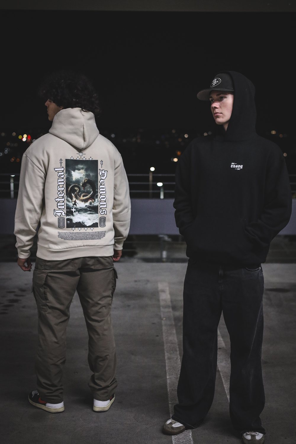 Two people wearing hoodies with visible branding in a dark setting