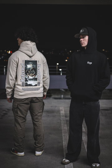 Two people wearing hoodies with visible branding in a dark setting
