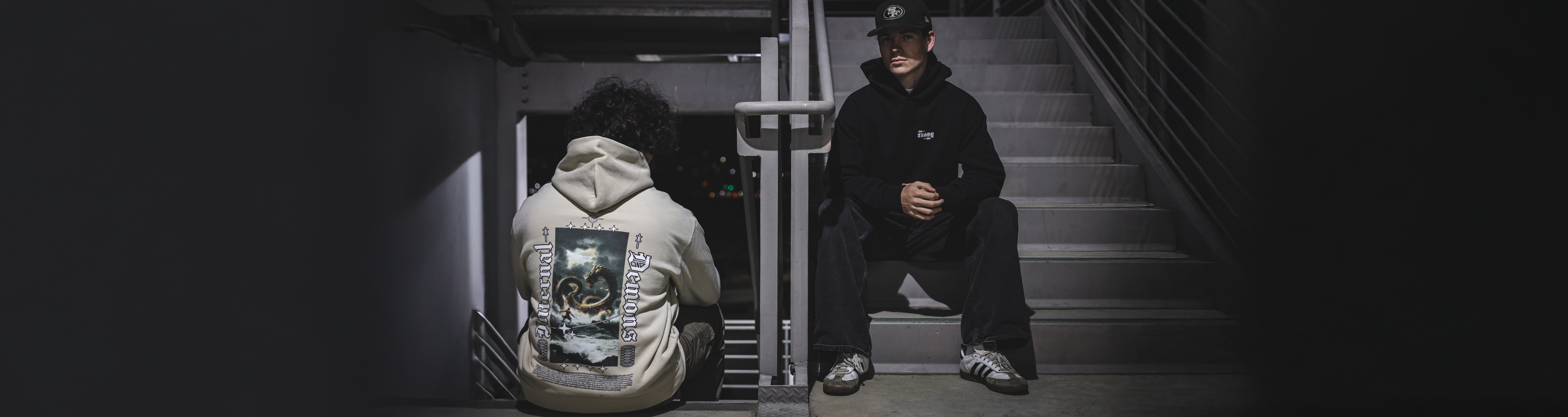 Two people sitting on a staircase in a dimly lit area