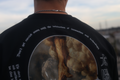 Closeup rear photo of a black oversize tee focused on the curved top text that says 